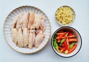 准备好所有食材。鸡翅洗净对半切开，青红椒切滚刀块，大蒜切末。