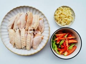 准备好所有食材。鸡翅洗净对半切开，青红椒切滚刀块，大蒜切末。