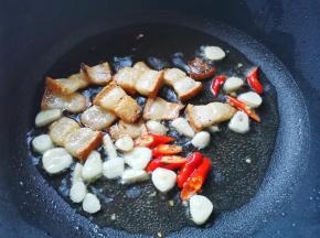 锅中放入腊肉煎出油，加入大蒜小米椒爆香，