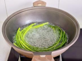 锅中水烧开，放入蒜苔焯水。