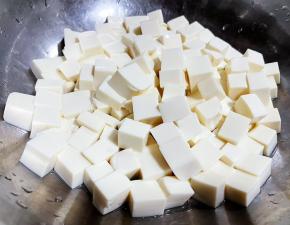 嫩豆腐切成大小均匀的小块，放入开水中烫一下后立即放入冷水中凉，在沥干水分备用。