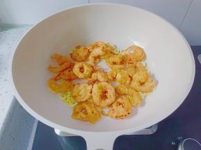 锅里放少许食用油，下蒜片炒香，加入炸好的虾仁