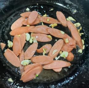 另起锅倒入底油加热，放入蒜爆香，再放入香肠炒至变色。