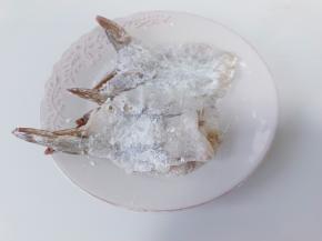 腌好的对虾裹一层淀粉，用擀面杖轻轻拍扁